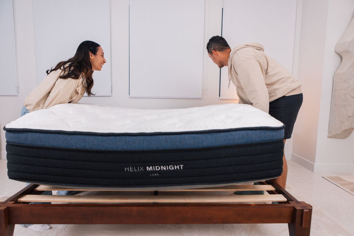 A man and a woman carrying the Helix Midnight Luxe Mattress.