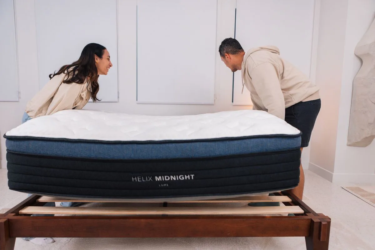 A man and a woman carrying the Helix Midnight Luxe Mattress.
