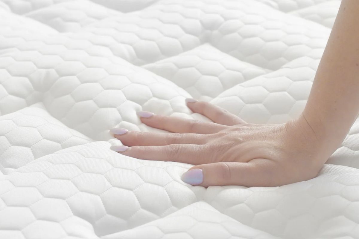Hand pressing Brooklyn Bedding Signature Hybrid mattress during trial period before deciding on return
