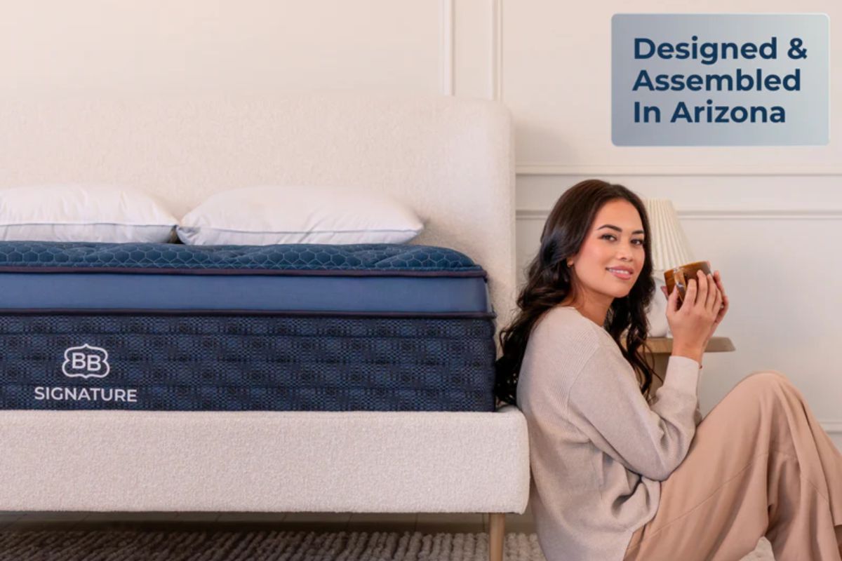 The Brooklyn Bedding Signature Hybrid with a woman sitting next to it "designed and assembled in arizona".