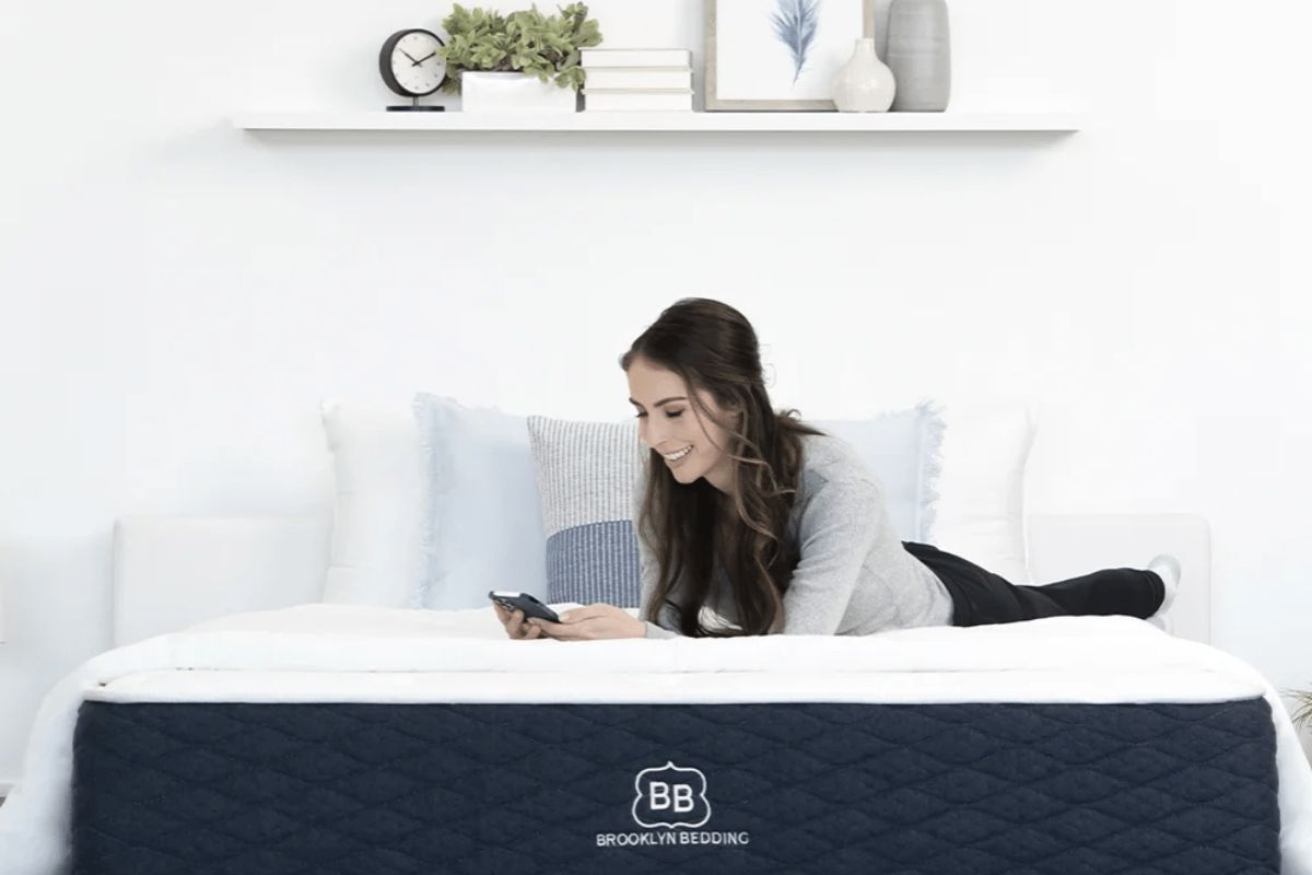 Woman relaxing on Brooklyn Bedding Signature Hybrid mattress showing everyday use and real customer experience
