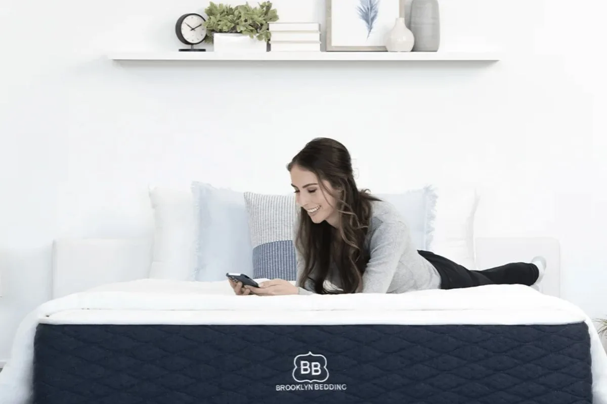 Woman relaxing on Brooklyn Bedding Signature Hybrid mattress showing everyday use and real customer experience