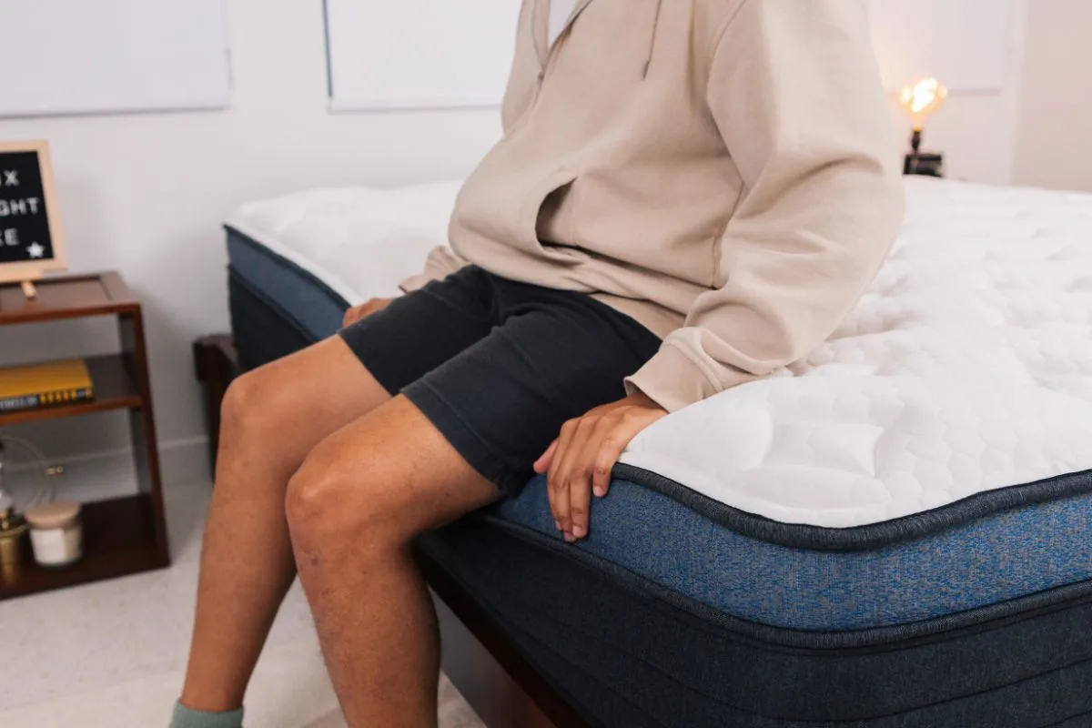 A man sitting on the edge of a bed.