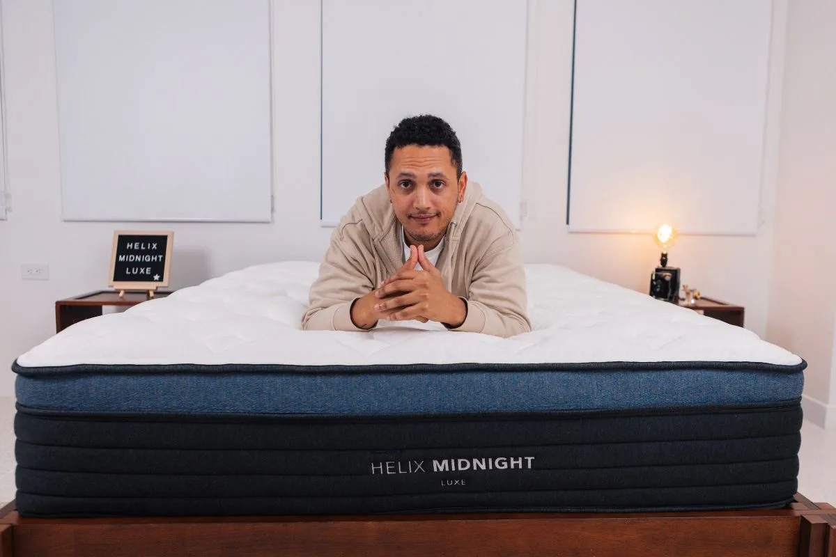 A man in comfortable clothes lying on his stomach the Helix Midnight Luxe.