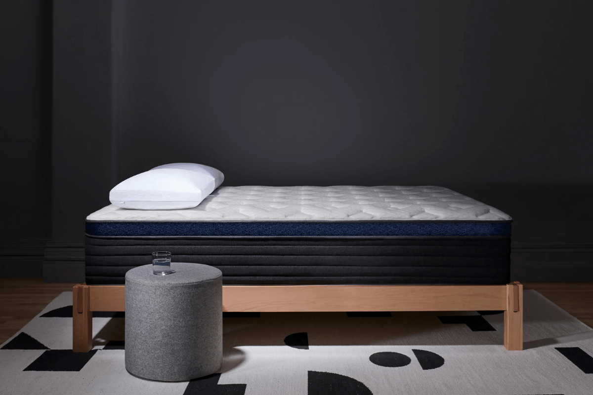 Helix Midnight Luxe mattress on wooden bed frame with pillow and bedside stool