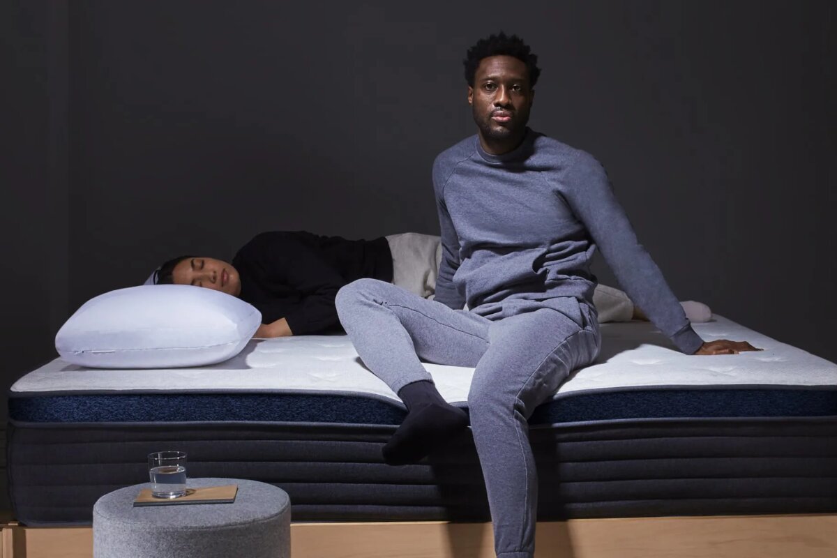 couple using Helix Midnight Luxe mattress with one person sitting and another lying down demonstrating comfort and support