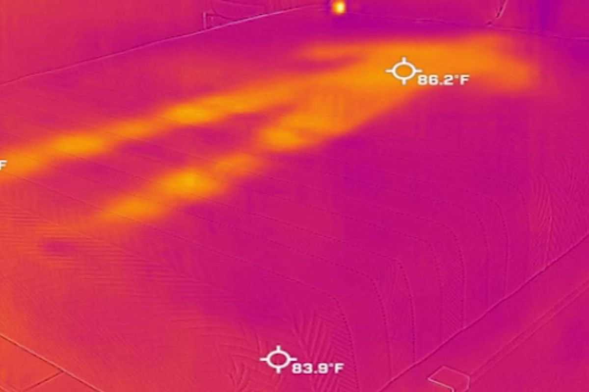 A heat image of a bed with a barely visible outline of a person.