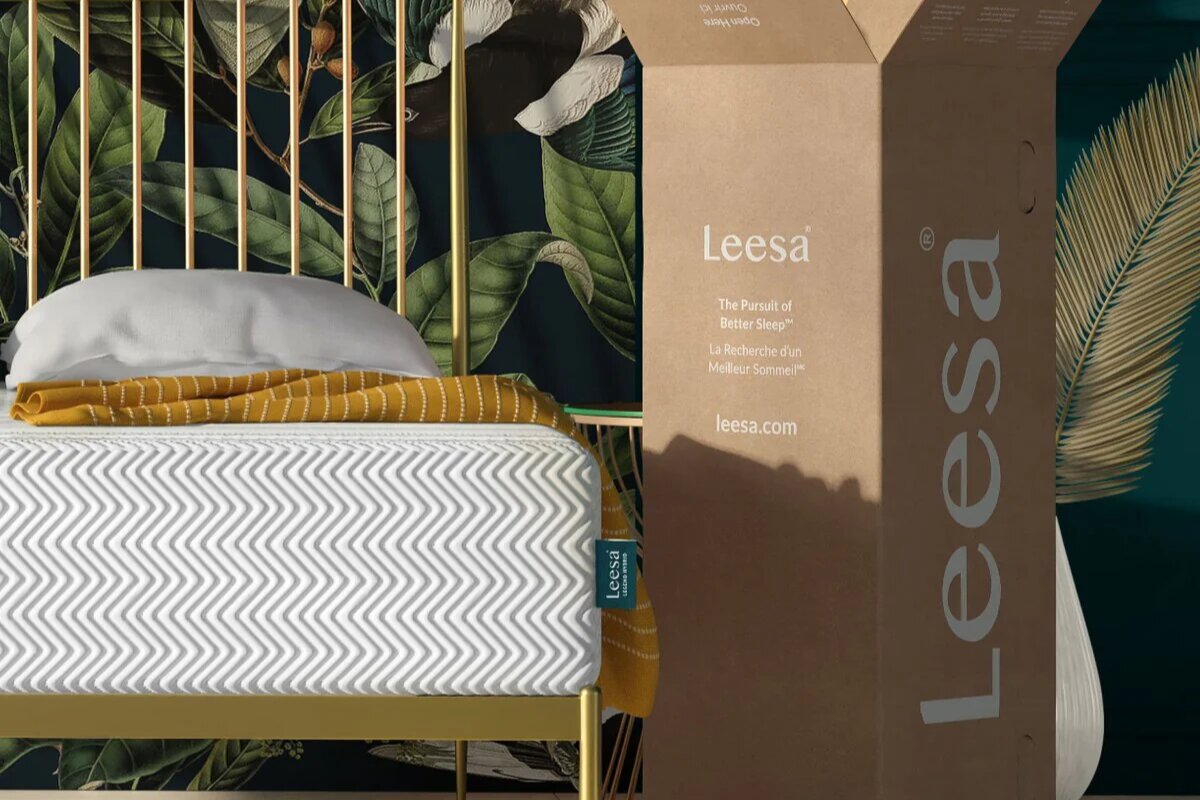 Leesa Legend Hybrid mattress on gold bed frame next to branded delivery box in stylish bedroom setting