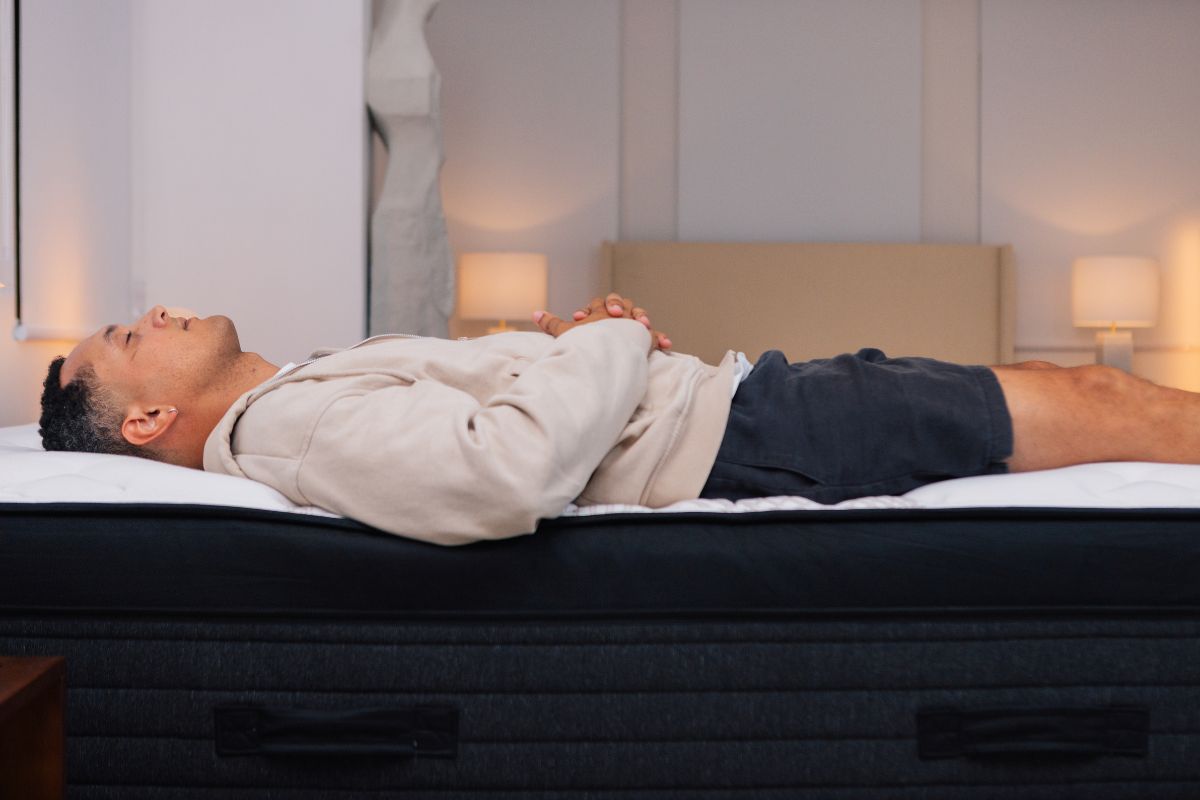 A man in comfortable clothes lying down on a mattress.