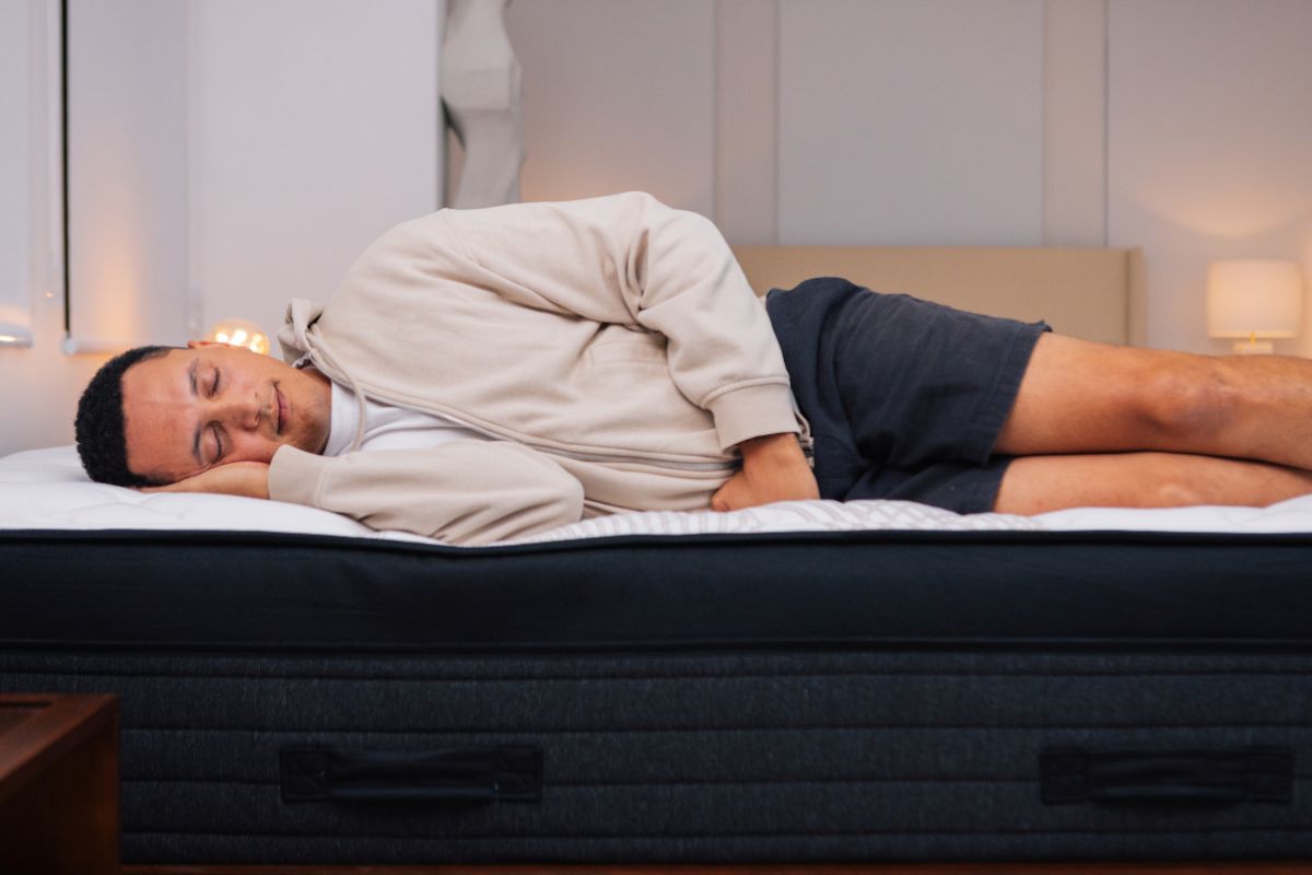 A man in comfortable clothes lying down on a mattress.