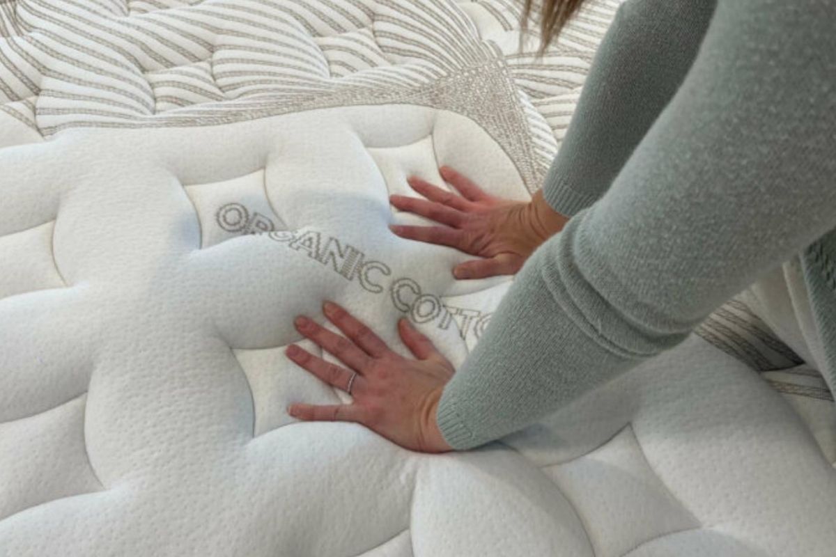 Hands pressing into Nolah Evolution 15 organic cotton cover highlighting breathable and non-toxic materials for safer sleep