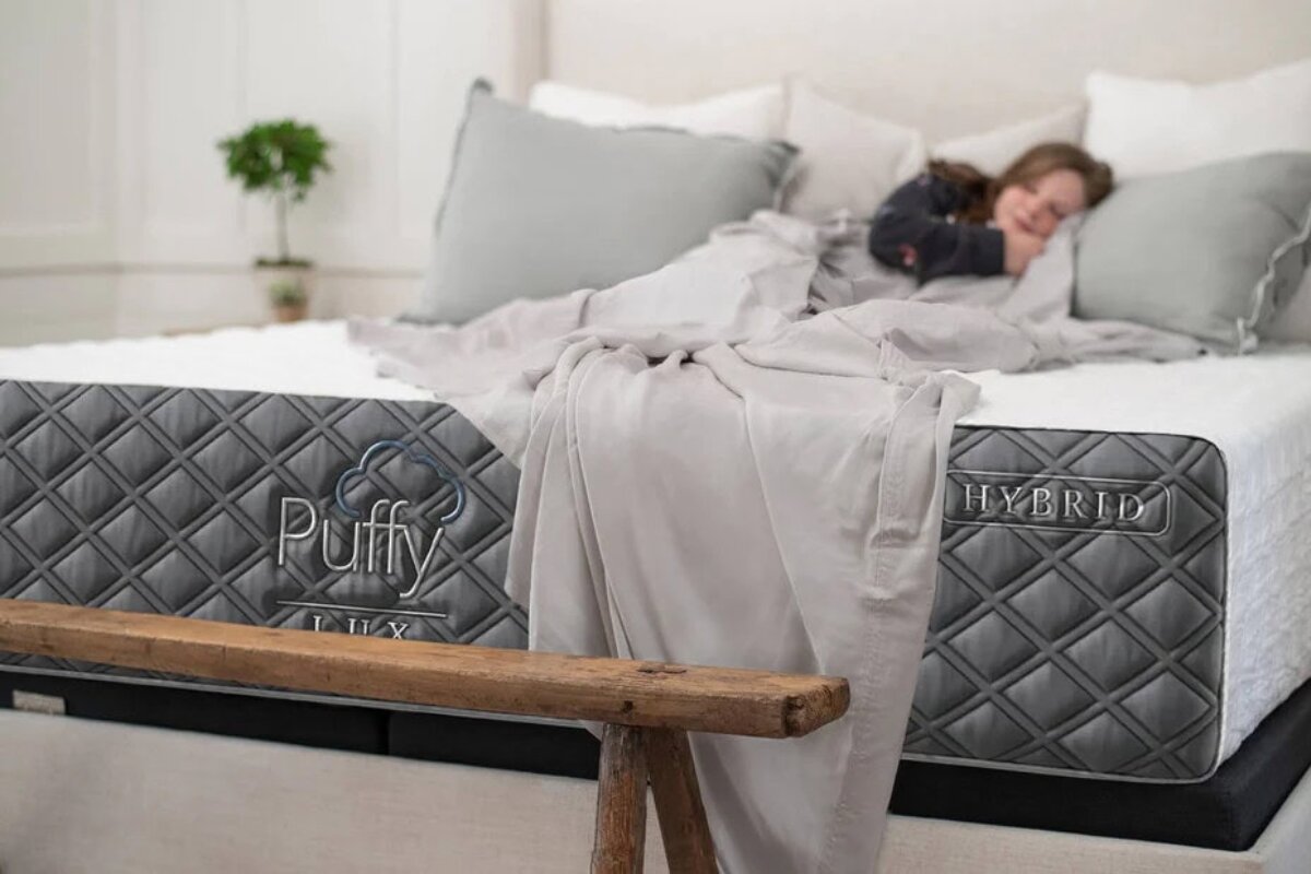 A woman lying down on the Puffy Lux mattress.