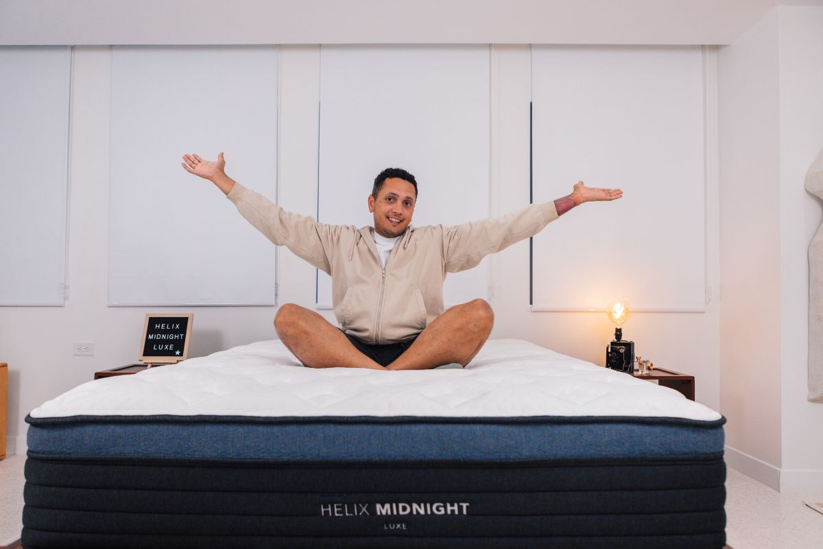 A man in comfortable clothes with his arms out sitting on the Helix Midnight Luxe.