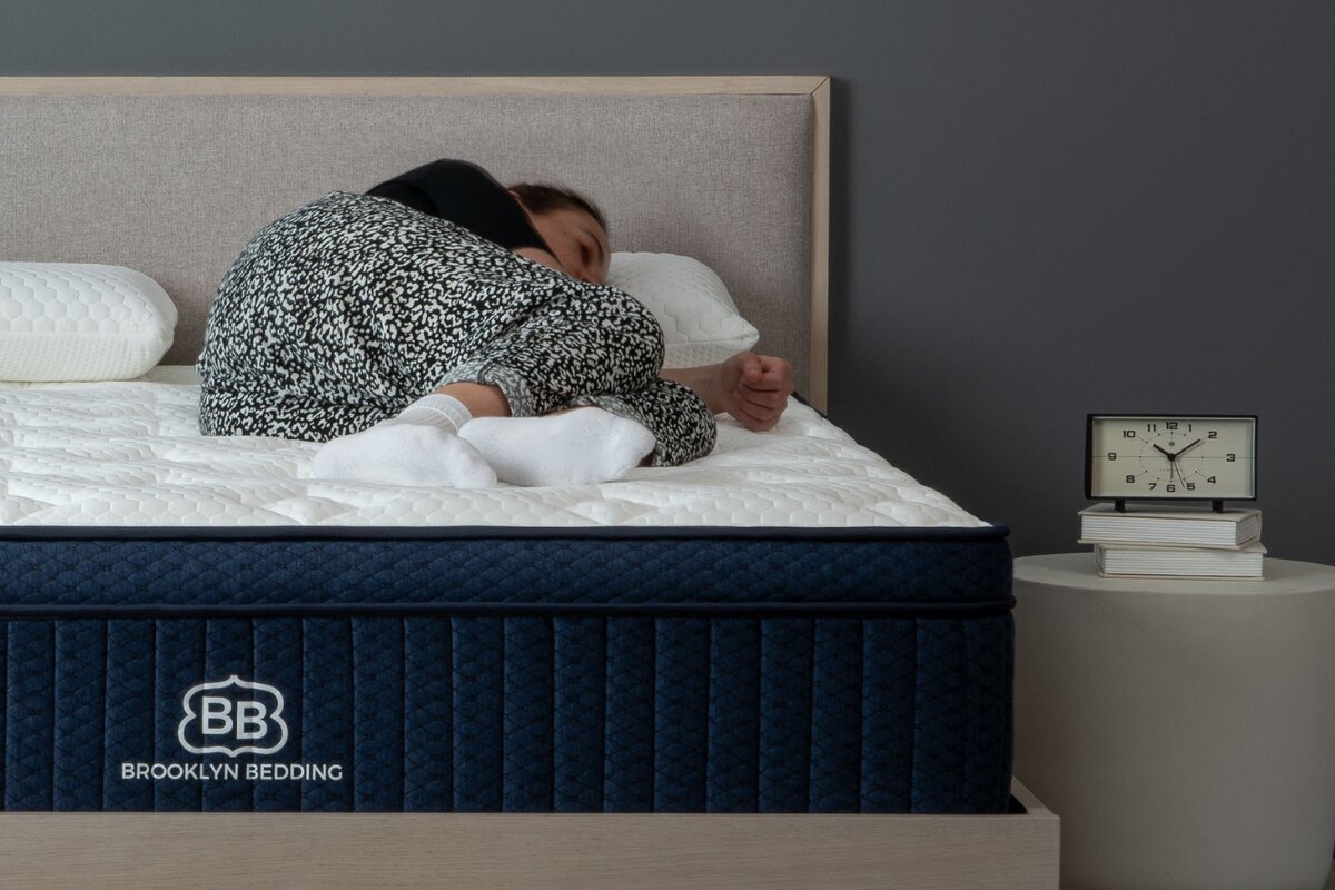 Person lying on Brooklyn Bedding Aurora Luxe Cooling mattress demonstrating side sleeping comfort and pressure relief