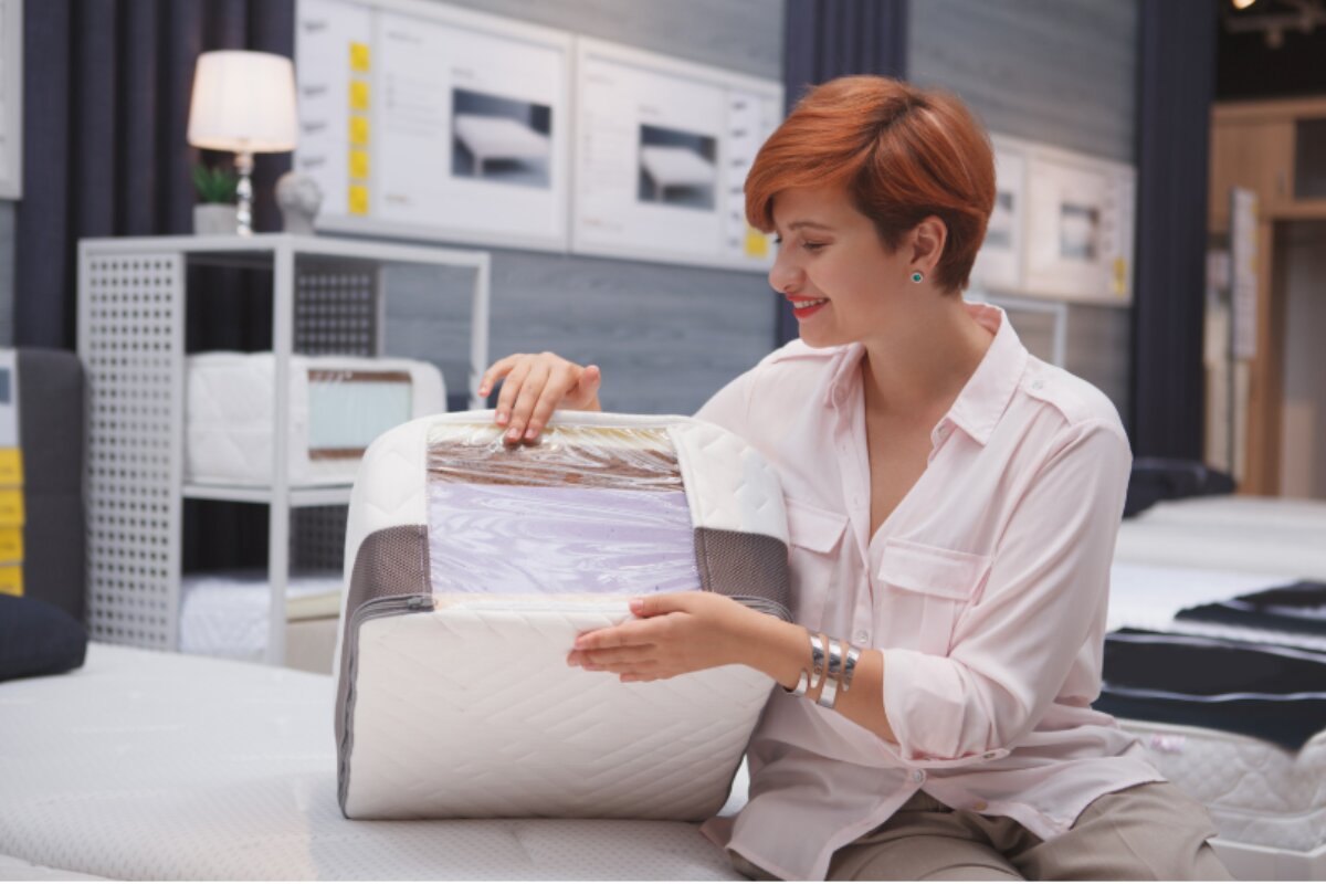 woman in mattress store inspecting memory foam mattress layers and materials