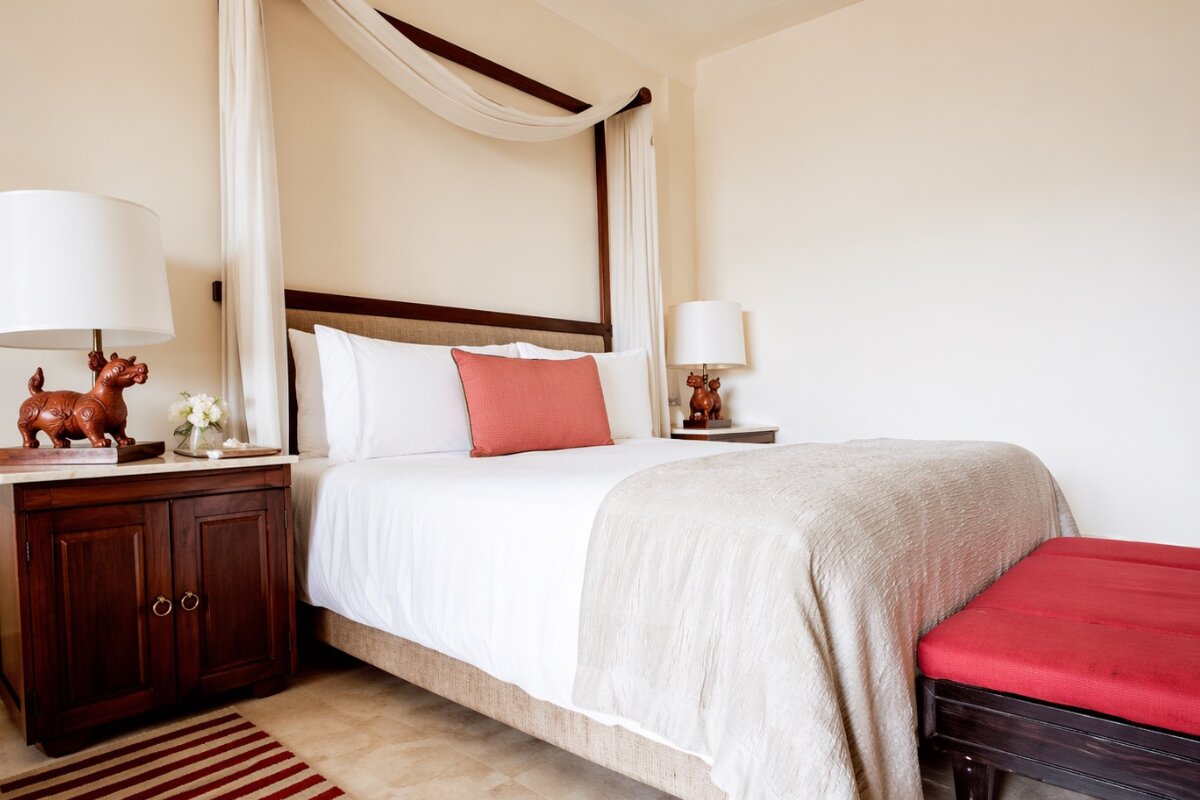 bright neutral bedroom with canopy bed, white bedding, wooden furniture, and soft natural lighting