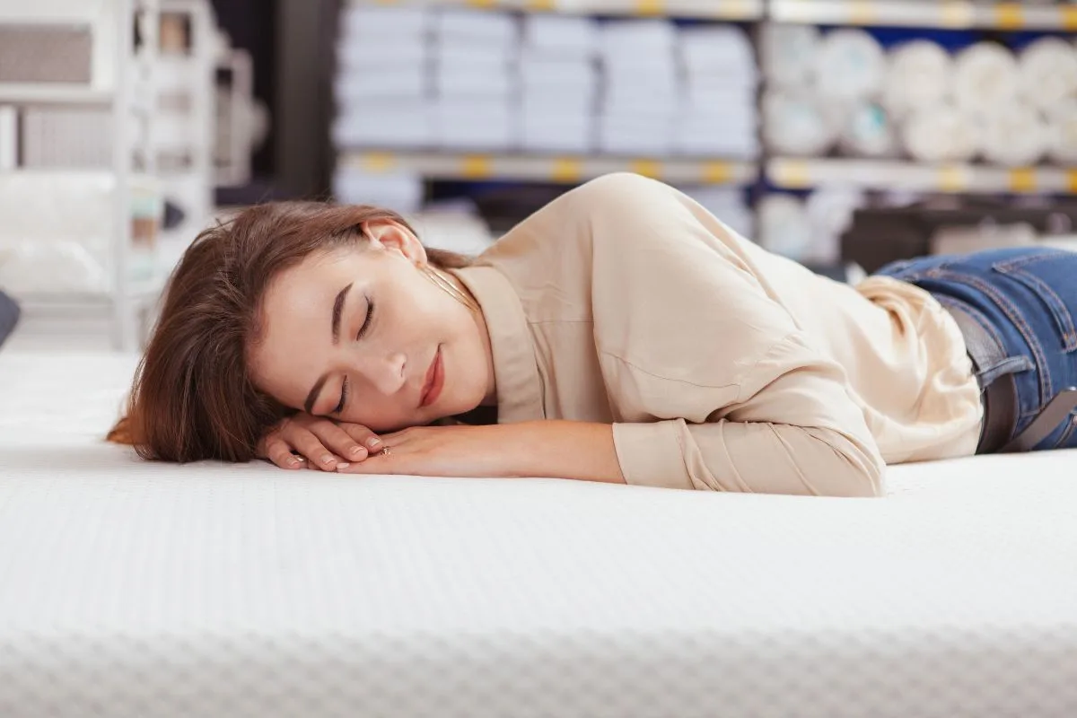 How Much is a California King Mattress? Person lying on mattress in store testing comfort before buying a California King mattress