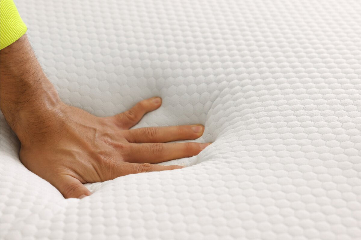 hand pressing into a foam mattress to demonstrate firmness and support