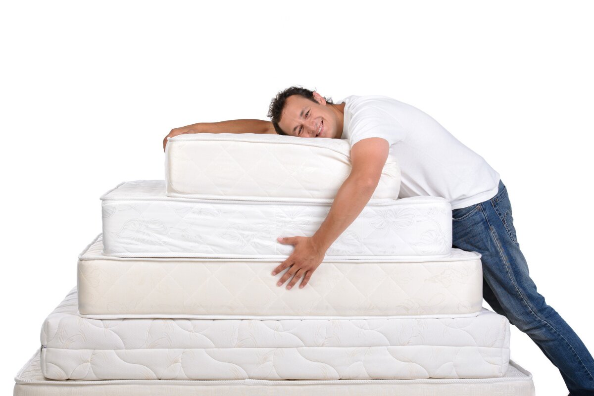 man hugging stacked mattresses of different sizes, showing comfort and mattress thickness comparison