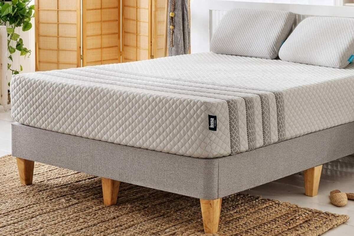 leesa sapira hybrid mattress on upholstered bed frame with wooden legs in bright bedroom setting