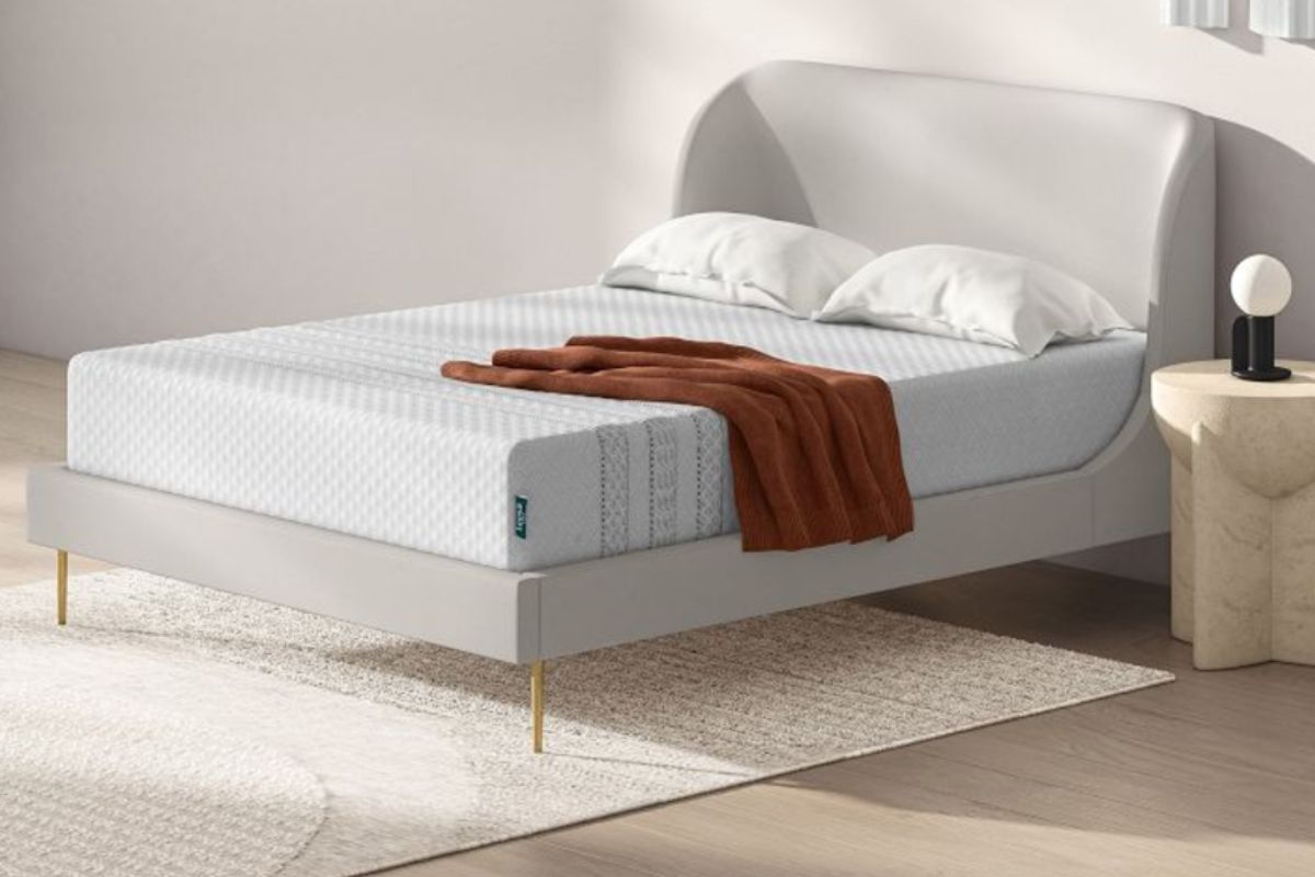 The Leesa Sapira Hybrid mattress in a bedroom with two pillows and a brown blanket.