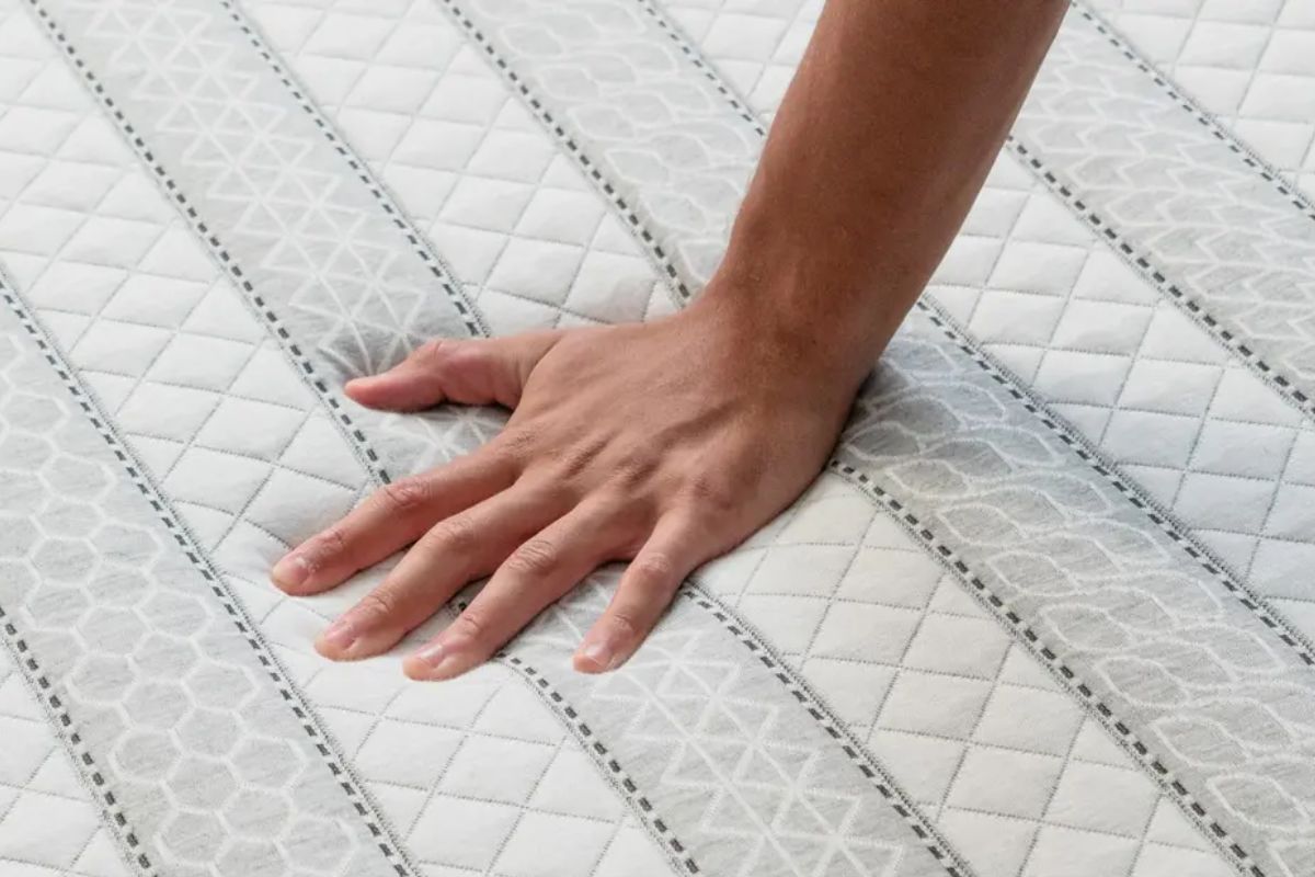 A person pressing on a mattress.