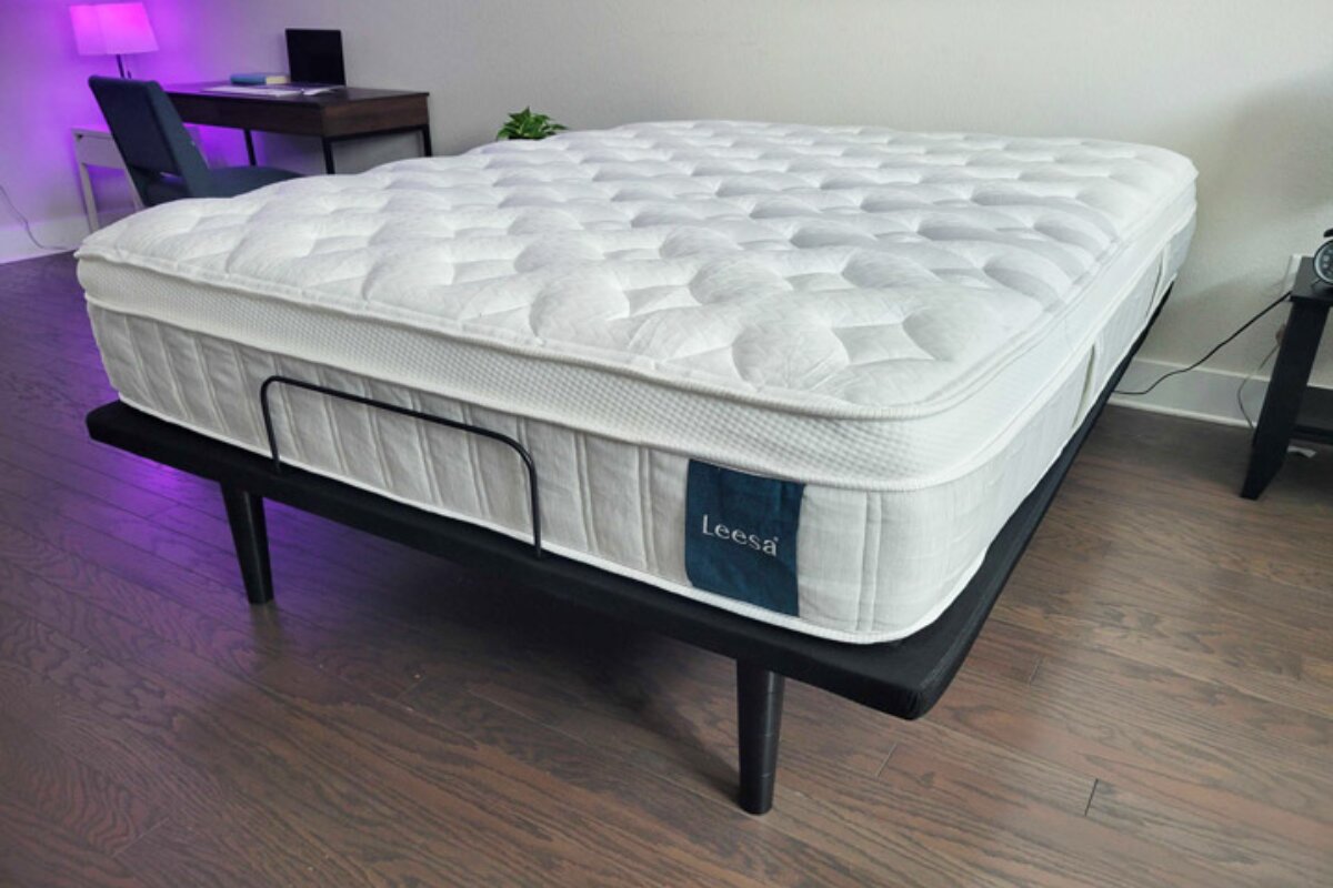 leesa sapira hybrid mattress on black platform bed in bedroom with wood flooring and ambient lighting