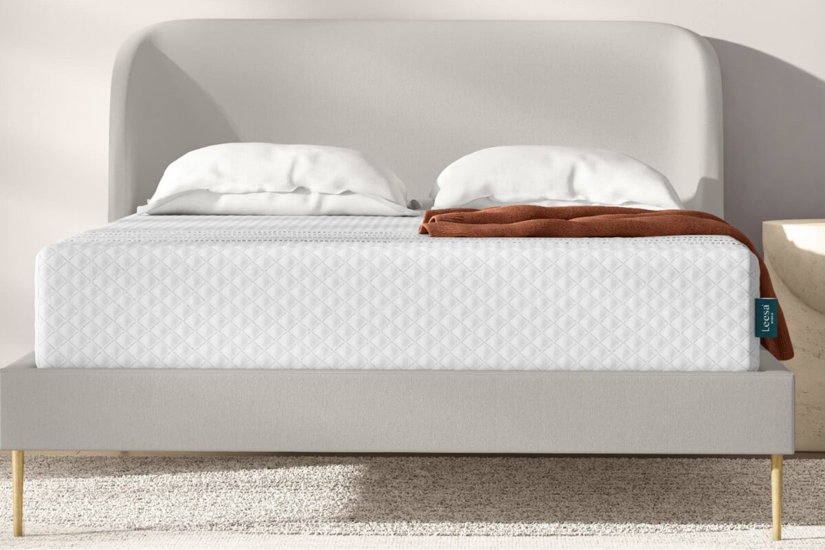 leesa sapira hybrid mattress on upholstered bed frame with white bedding and neutral bedroom setting