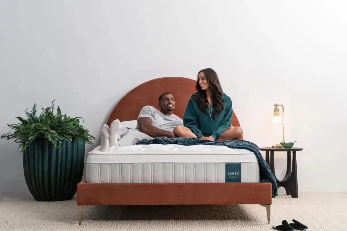 couple relaxing on a Leesa Sapira Hybrid mattress with upholstered bed frame in a modern bedroom setting