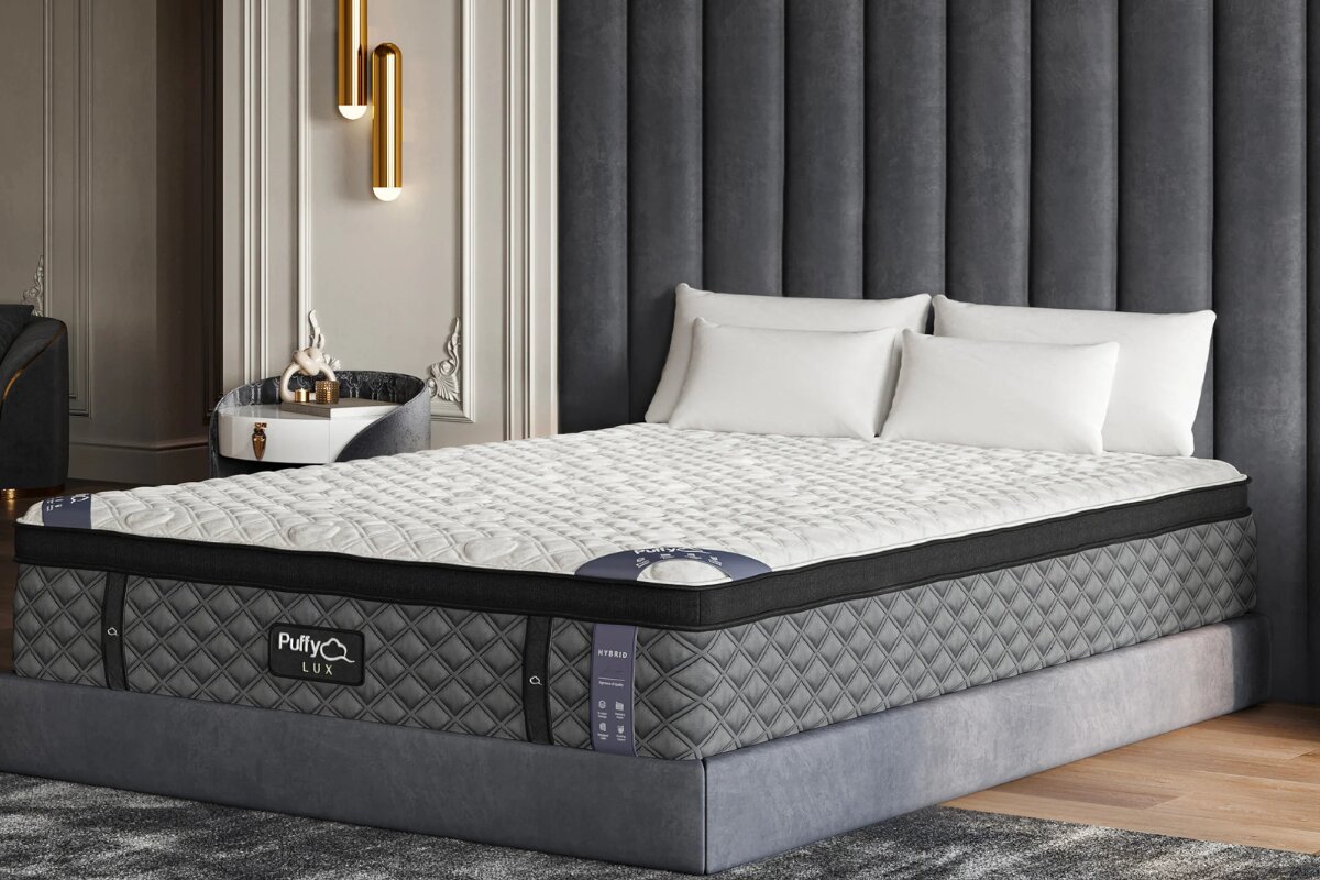 Puffy Lux mattress placed on a modern upholstered bed frame with gray headboard and white pillows in a stylish bedroom