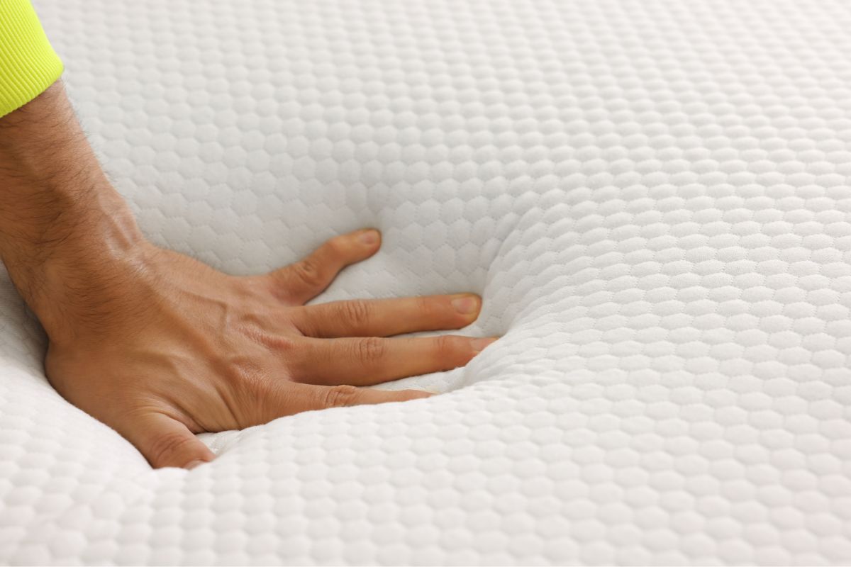 Hand pressing into mattress foam to show pressure relief and support for split California king mattress comfort