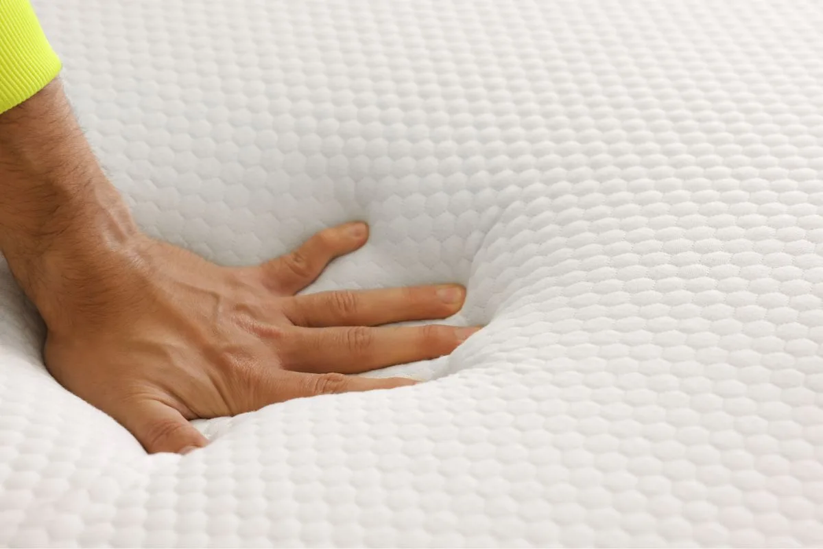 Hand pressing into mattress foam to show pressure relief and support for split California king mattress comfort