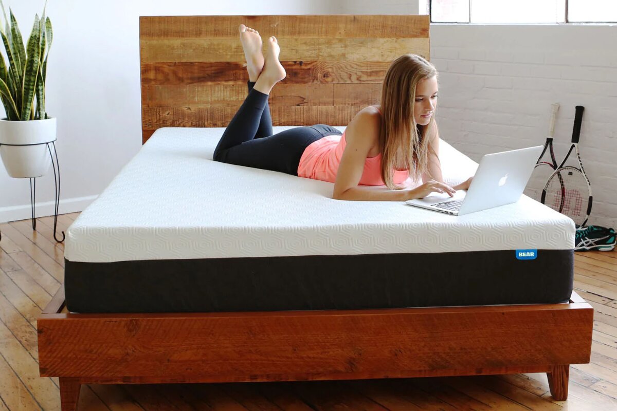 woman relaxing on bear original mattress while using a laptop in a modern bedroom
