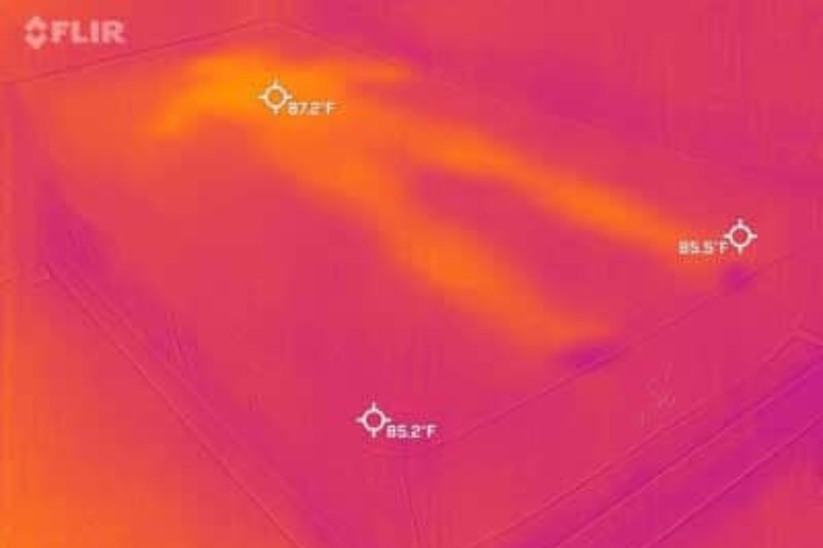 A heat image of a bed where a person laid down on it, barely visible.
