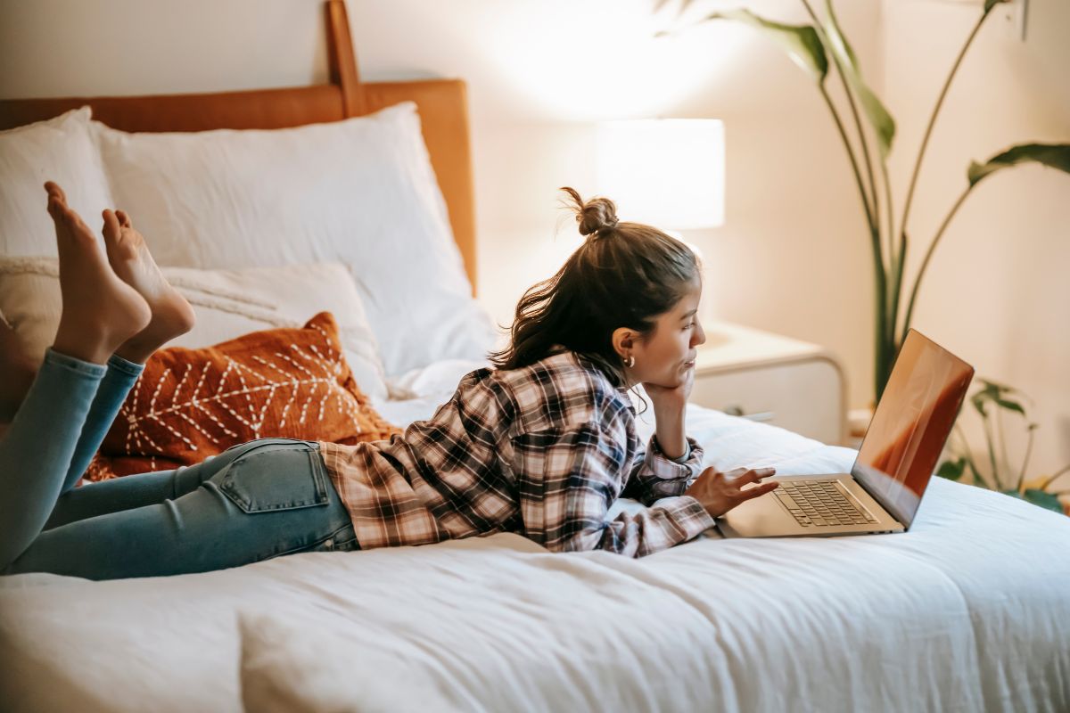 How Much Does a Full Size Mattress Weigh? Person lying on a bed using a laptop representing everyday use despite full mattress weight