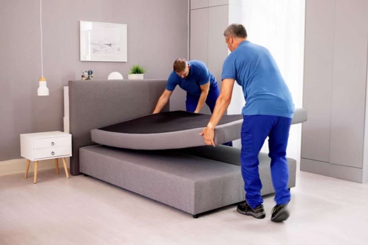 How Much Does a Full Size Mattress Weigh? Two people lifting a mattress onto a bed frame illustrating the weight of a full size mattress