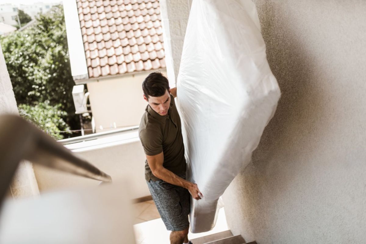 Person carrying a mattress upstairs illustrating how heavy a twin XL mattress can feel