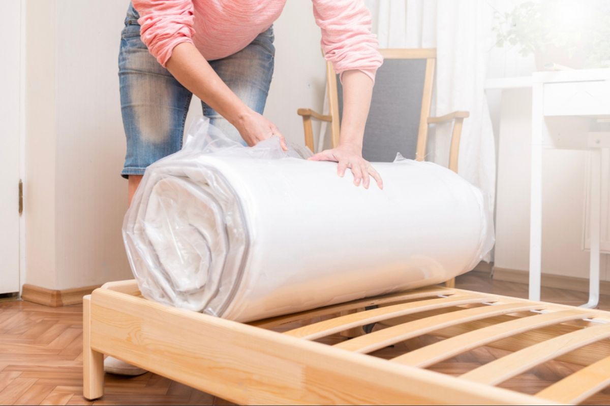 Rolled mattress being unpacked on a frame demonstrating compressed weight and handling of a twin XL mattress