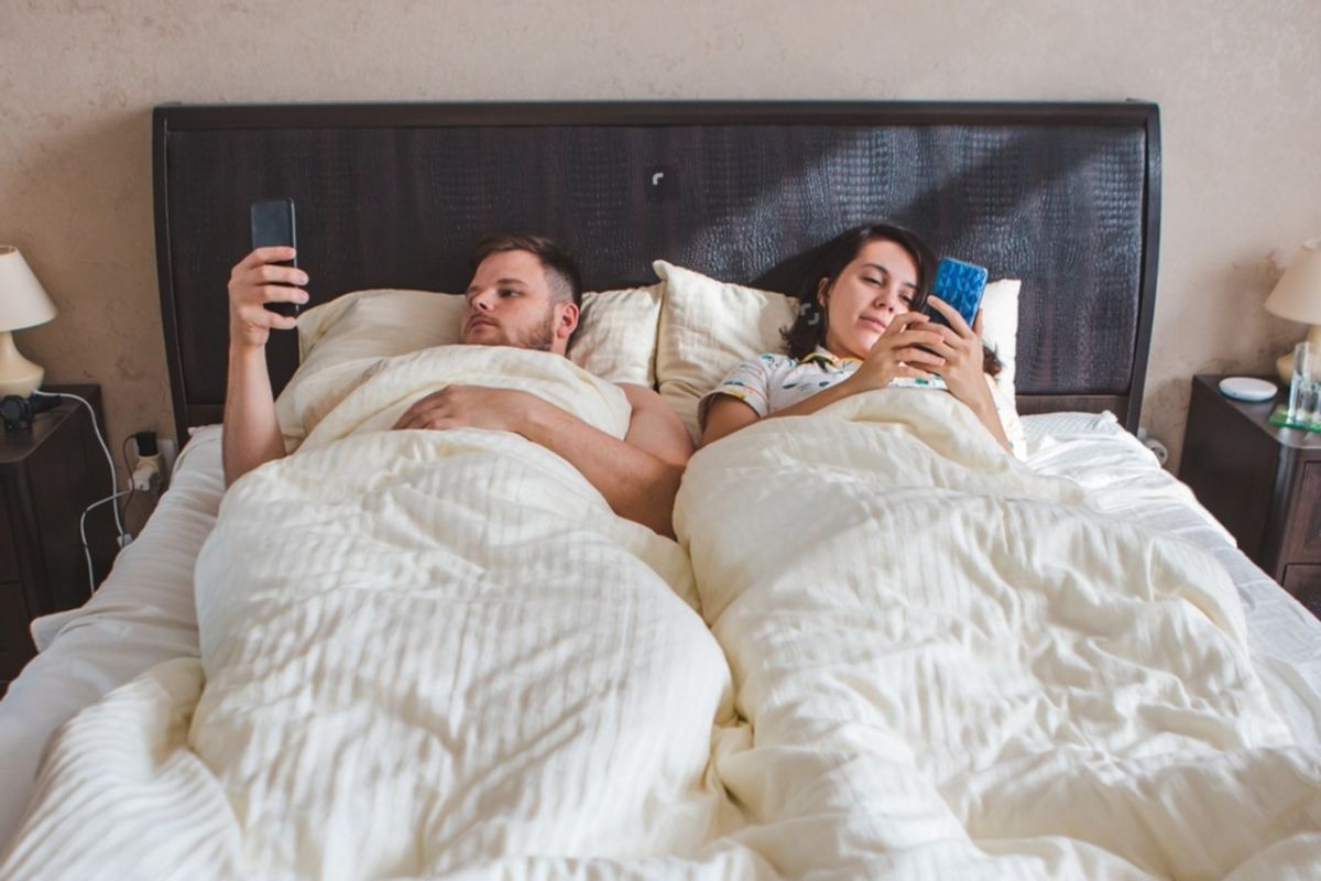 Couple lying in bed highlighting limited space width of a full size mattress for two sleepers