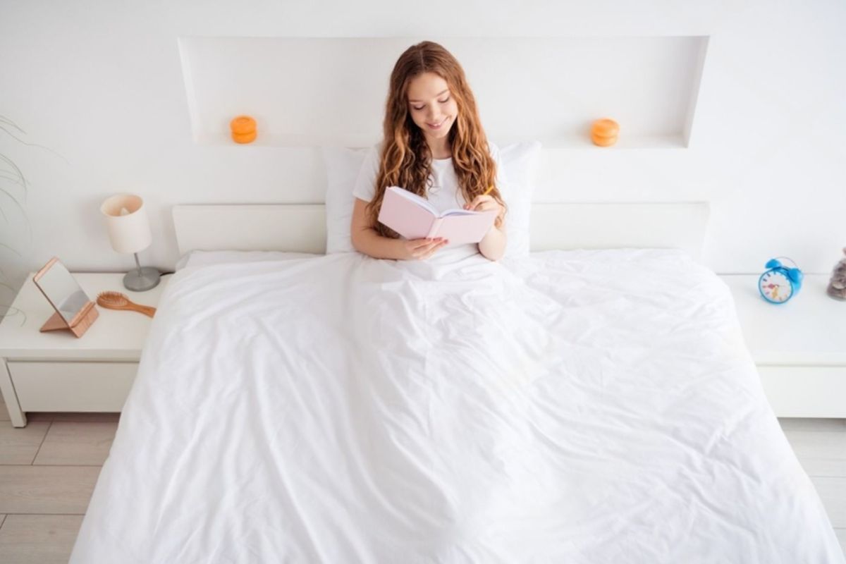 Person sitting on a bed illustrating usable space and width of a full size bed