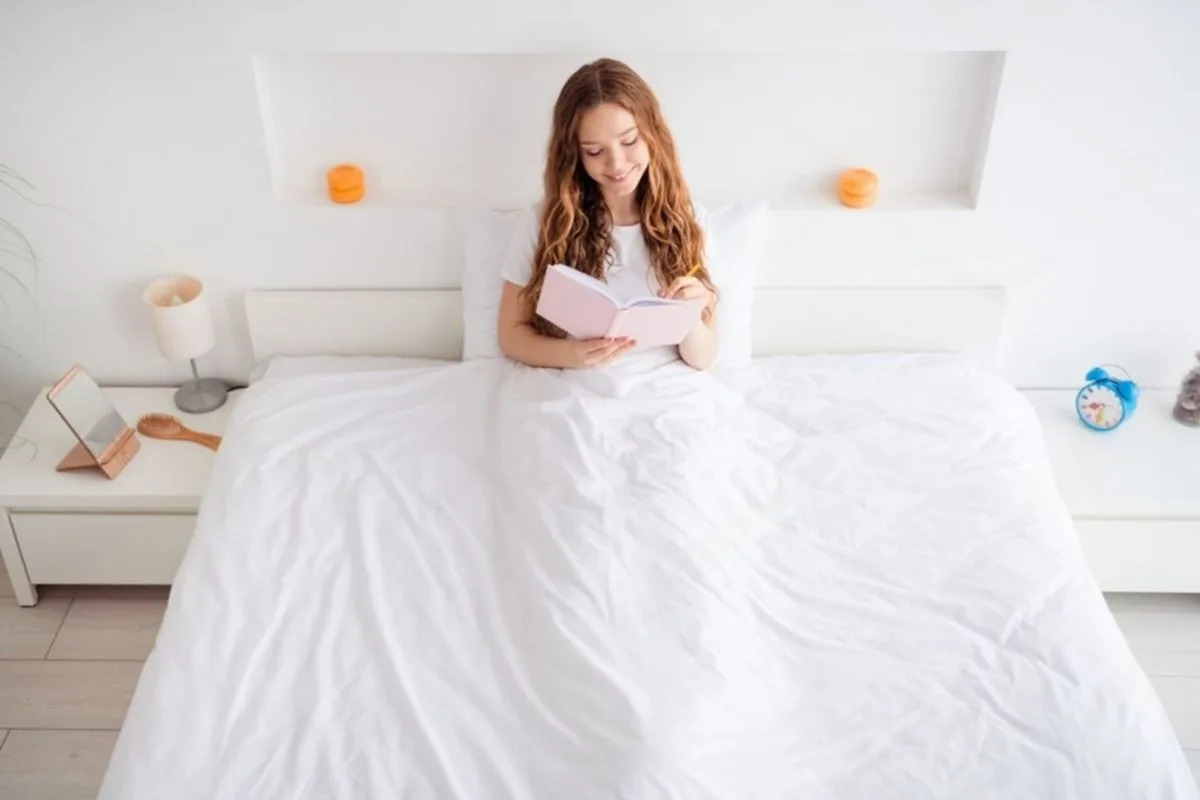 Person sitting on a bed illustrating usable space and width of a full size bed