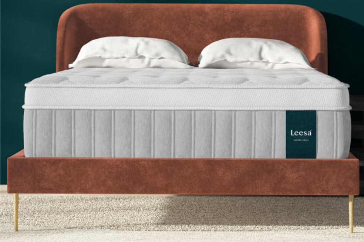 front view of the leesa sapira chill hybrid mattress on a brown upholstered bed frame with white pillows