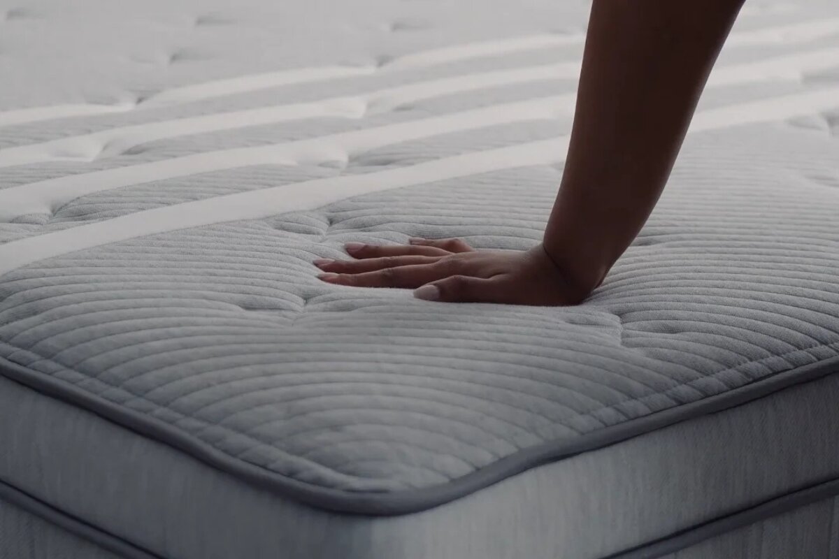 hand pressing into the plush surface of the leesa sapira chill hybrid mattress to show cushioning and support