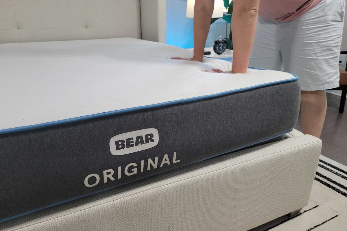 person pressing down on bear original mattress to test firmness and support