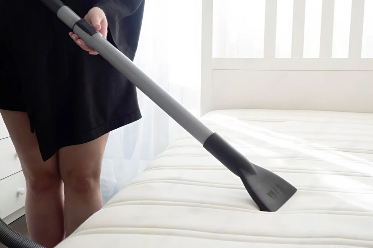 Vacuum cleaning a plush mattress surface as part of mattress maintenance to preserve support and prevent soft spots