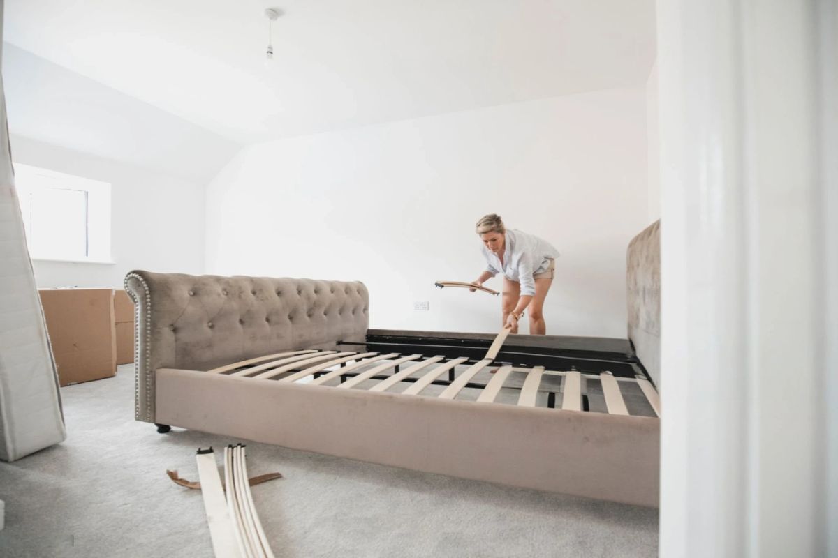 Person adjusting bed slats under a mattress to increase mattress firmness and stability