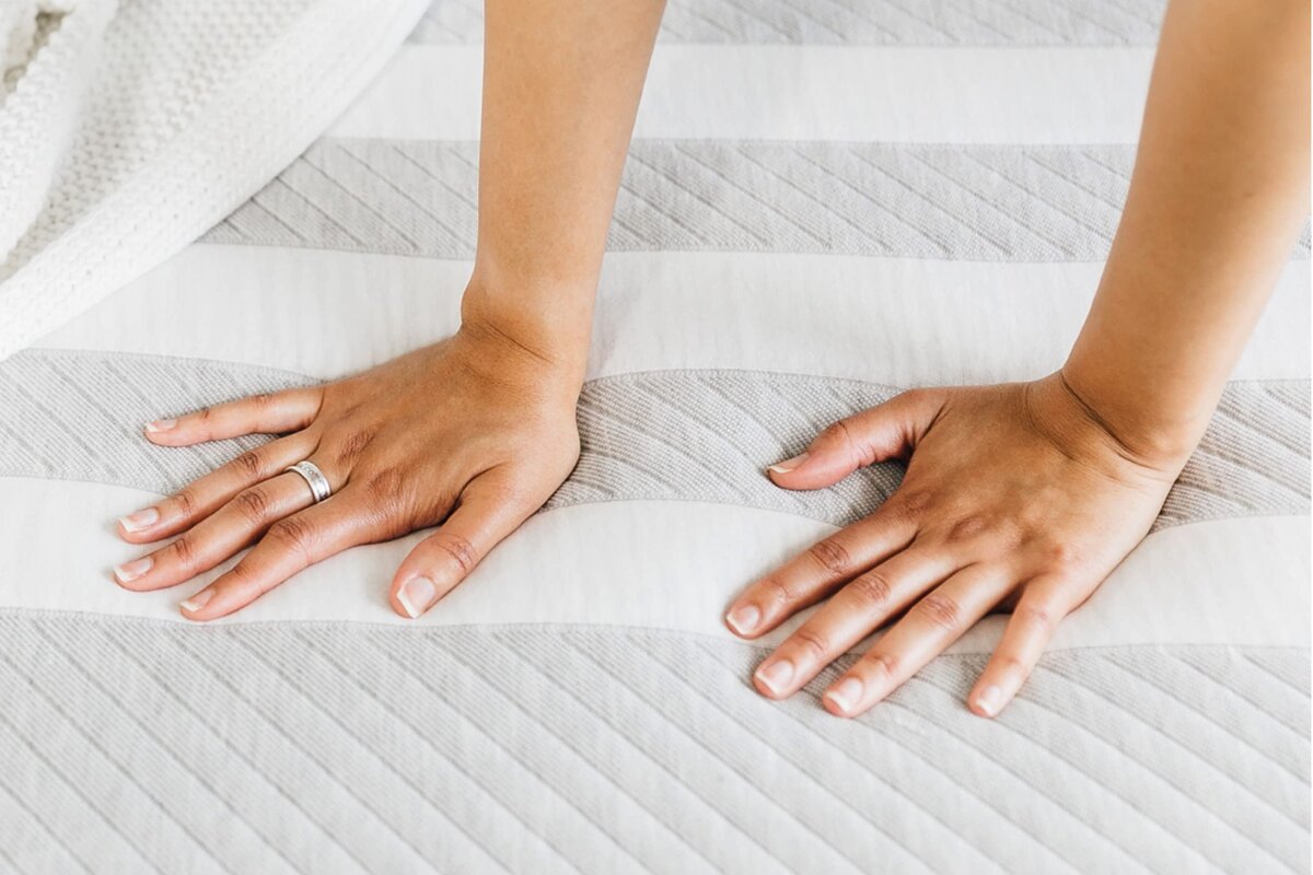 A person pressing on a mattress.