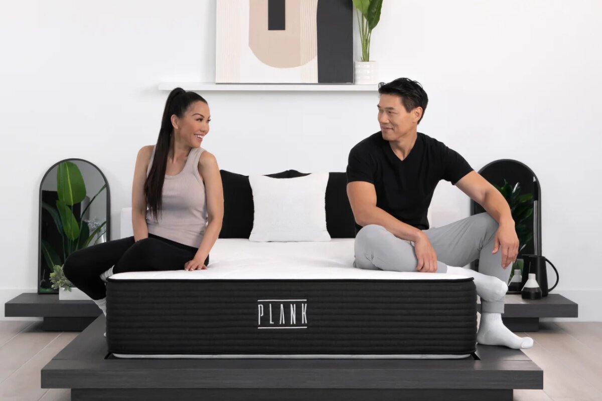 What to Expect in a Plank Firm’s Trial-Period plank mattress with two people sitting on opposite sides demonstrating motion isolation and support