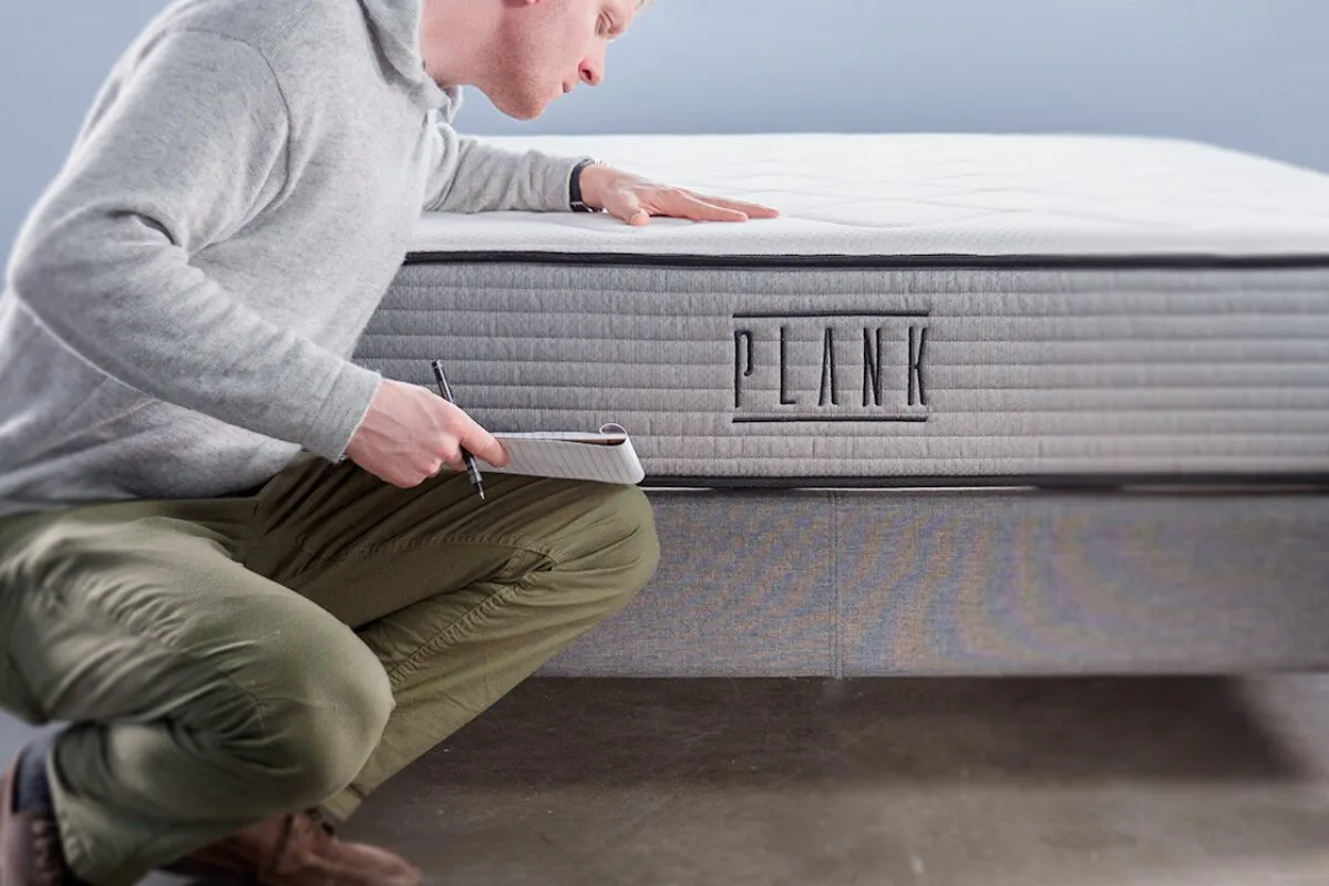How to Avoid Voiding a Plank Firm’s Warranty person inspecting a plank mattress and taking notes during a mattress evaluation or warranty assessment