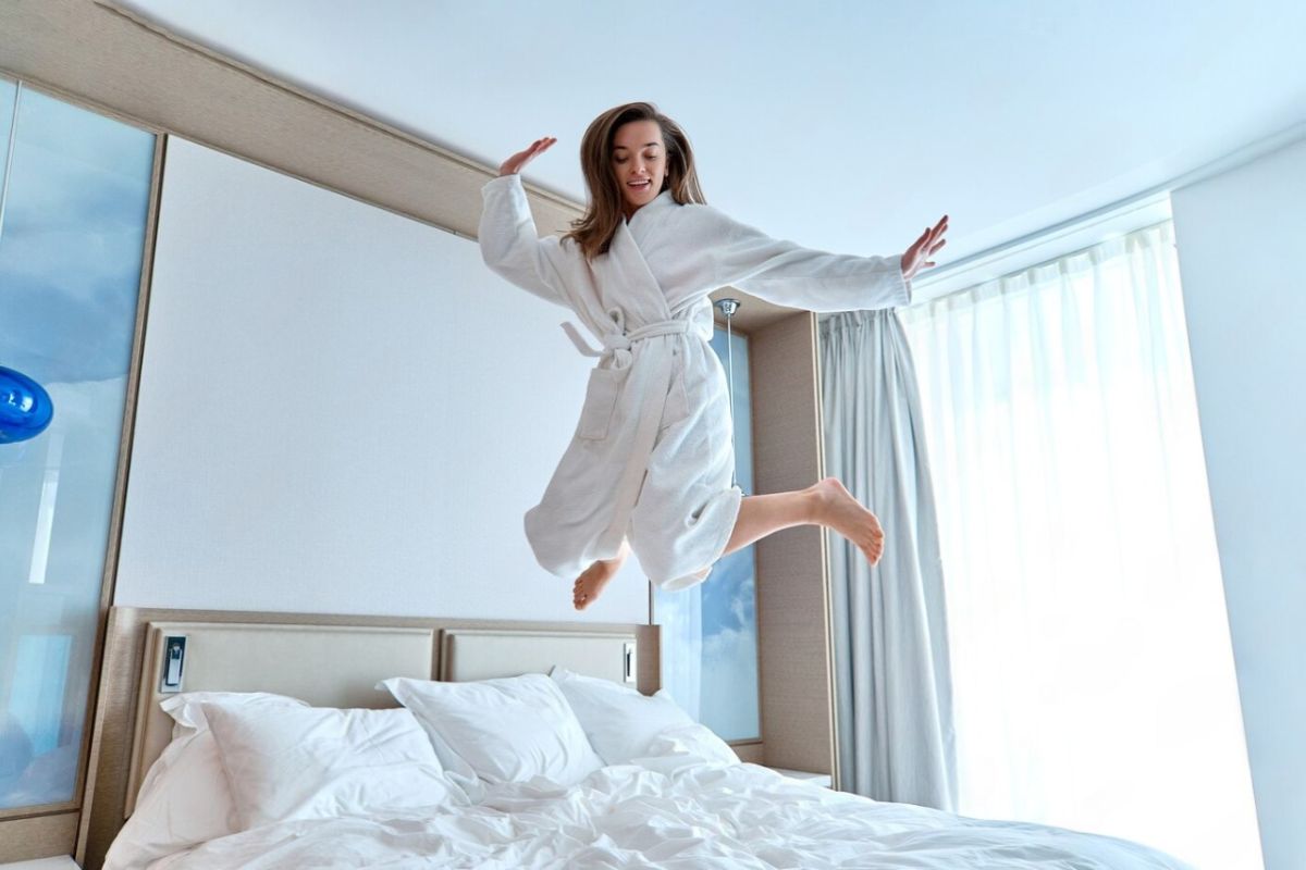 Woman jumping on a bed to represent the responsive comfort and balanced feel of a medium mattress